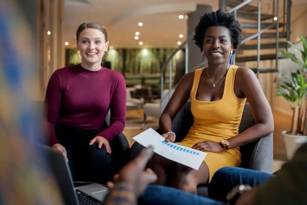 Two diverse young businesswomen smiling while discussing