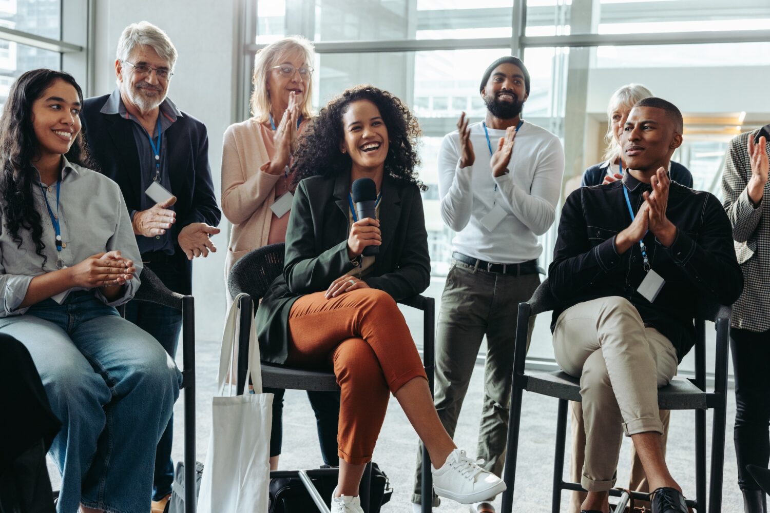 Happy professionals attending a panel discussion at a corporate event, engaged in conversation and applauding.